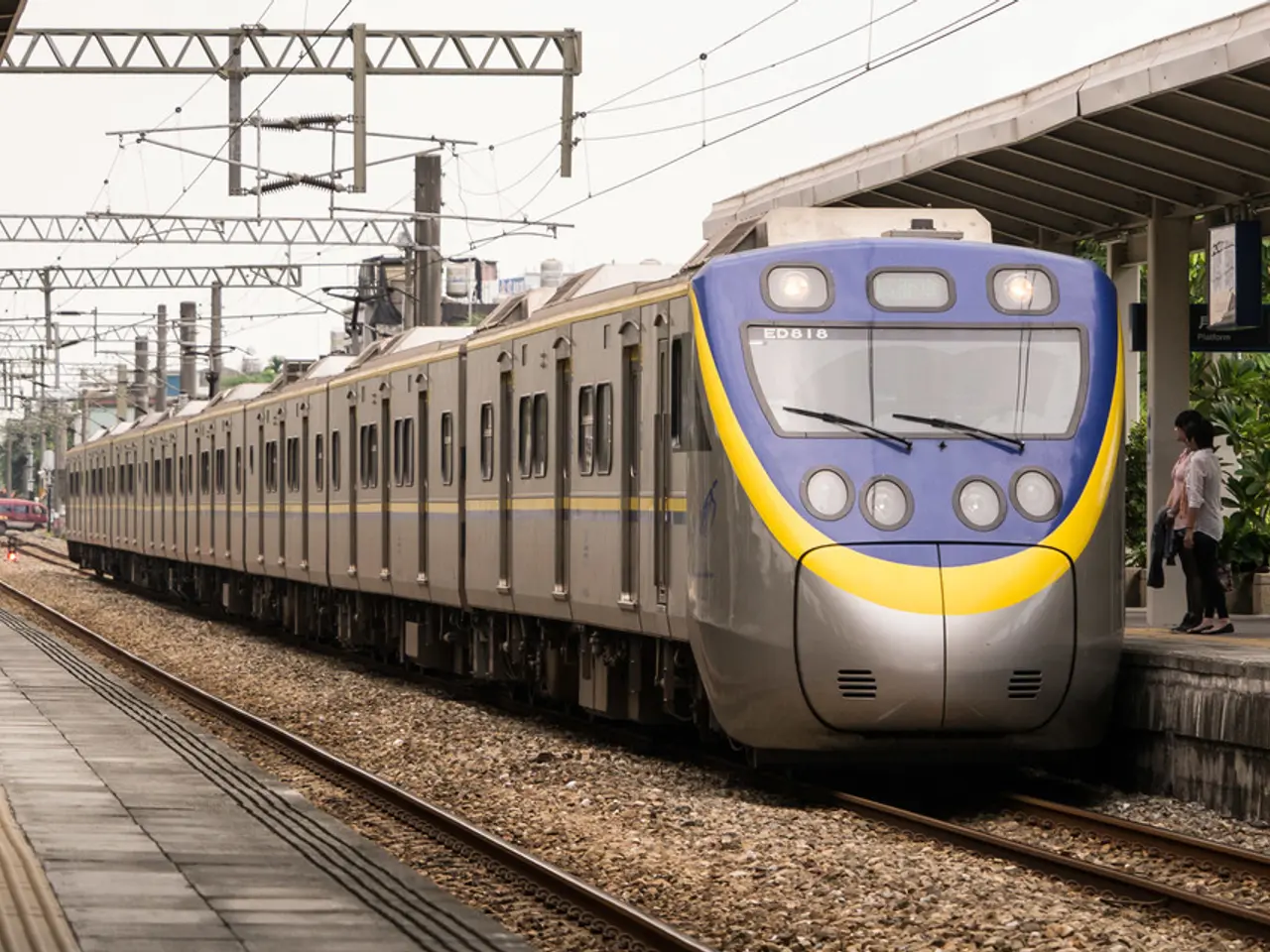 In the image there is a train on the track and beside the train few people were standing on the...