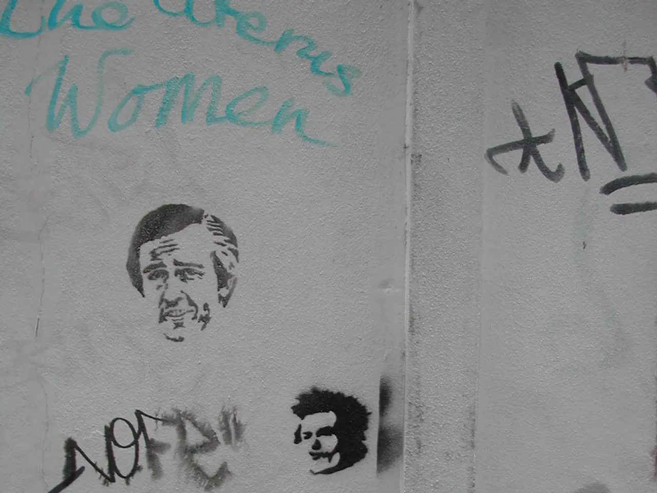 In this picture we can see there are some drawings and words on the wall and in front of the wall...