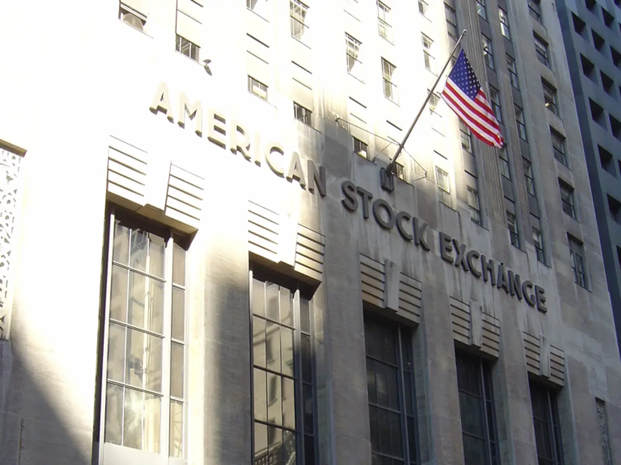 In this image there is a building. There is text on the building. There is a flag to the pole on...