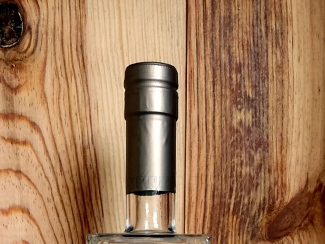 This picture shows a vodka bottle placed here. In the background, there is a wooden wall.