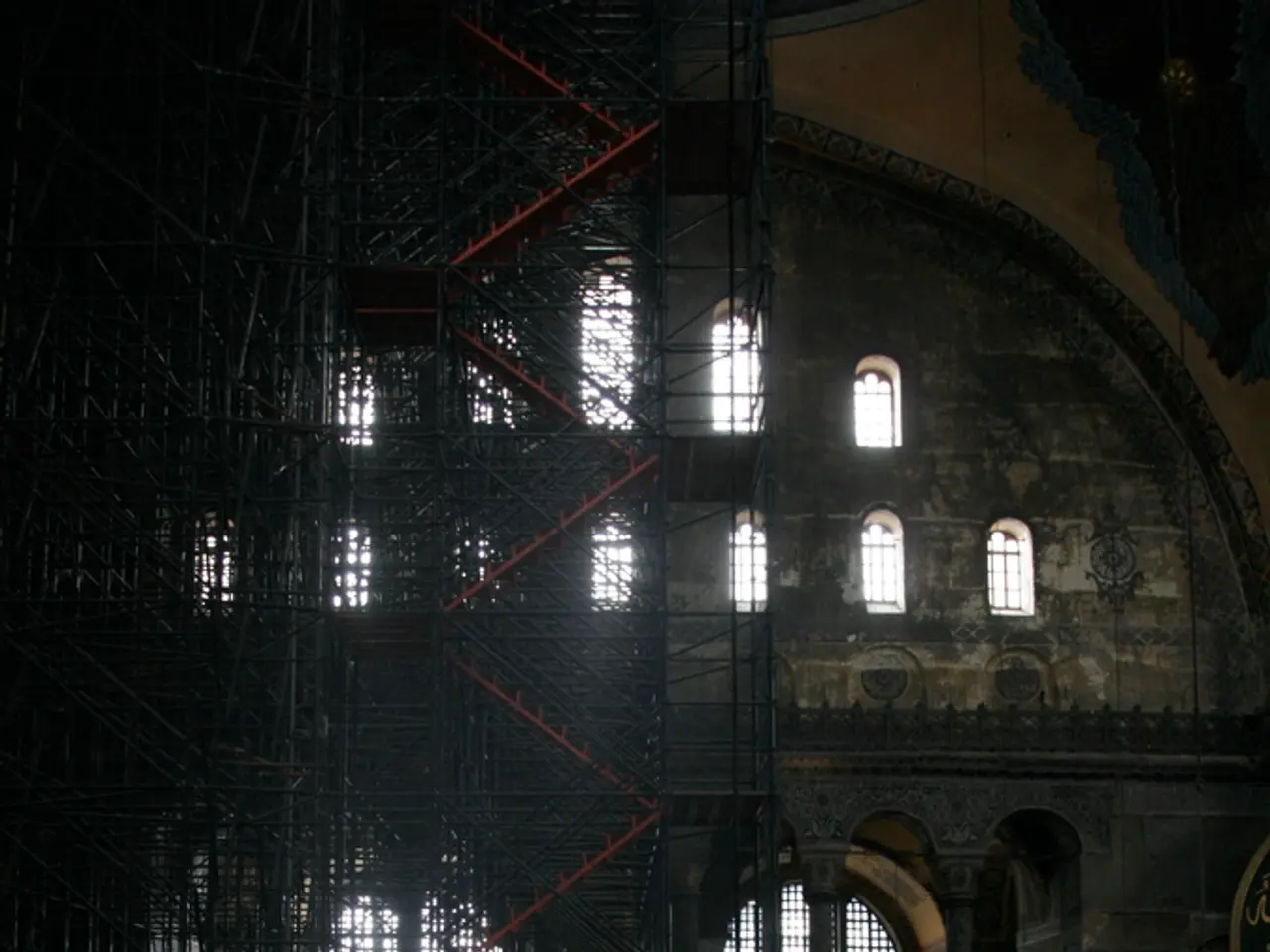 In this picture I can see a building with windows, there are iron grilles and stairs.