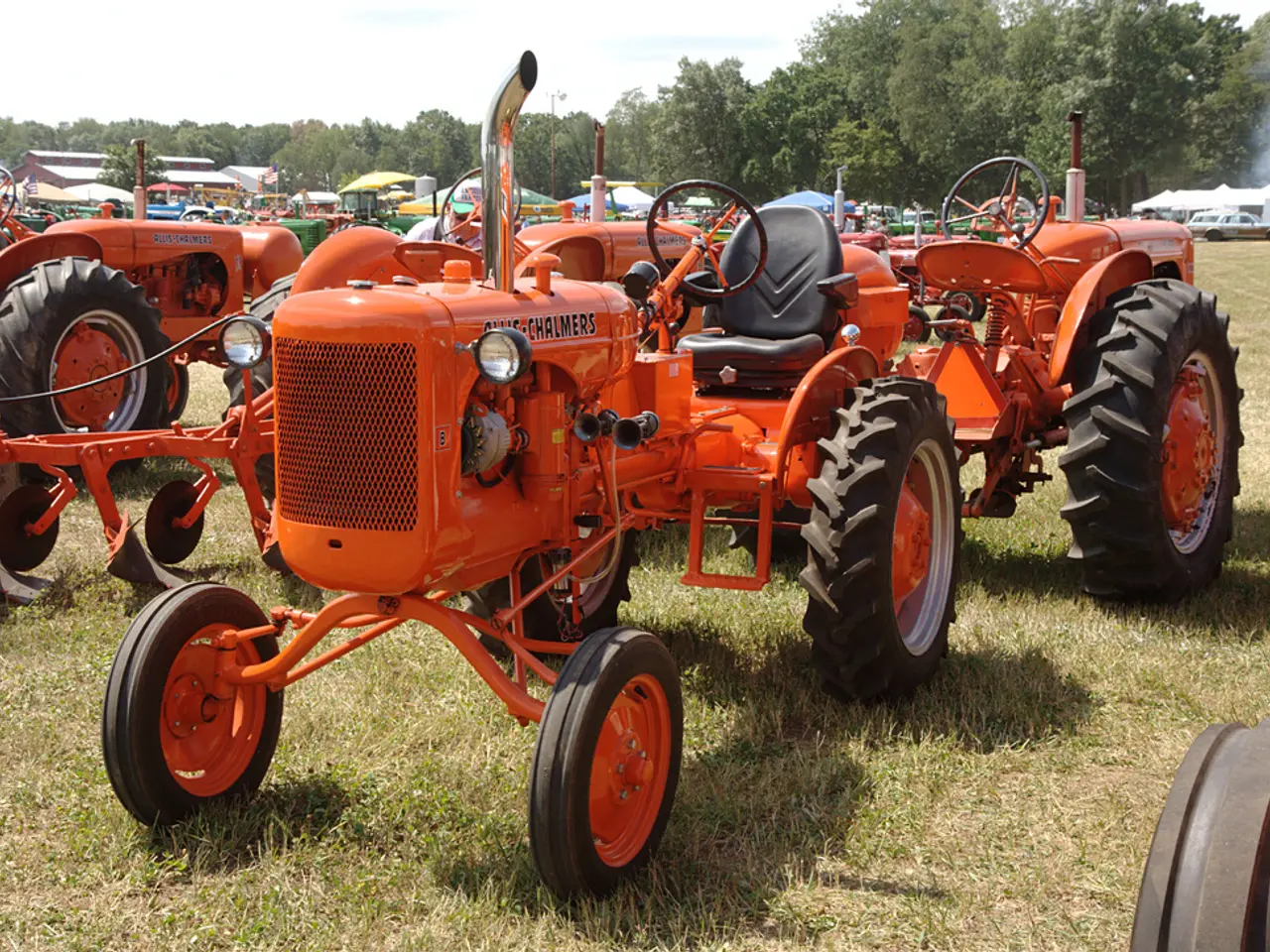 In this picture, we see tractors which are in orange color are parked in the garden. At the bottom...
