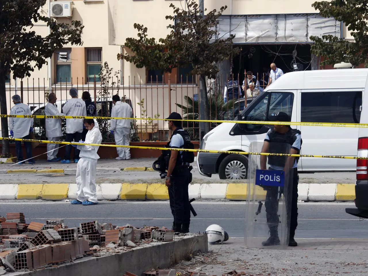 The image shows a group of police officers standing in front of a building with windows, surrounded...
