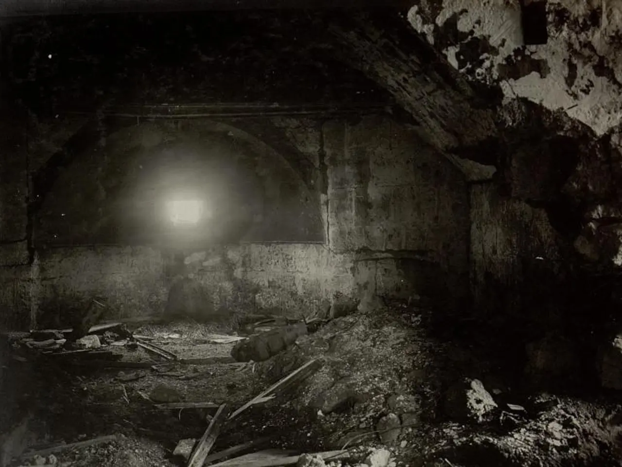 The image shows an old black and white photo of a tunnel with a light at the end, located in the...