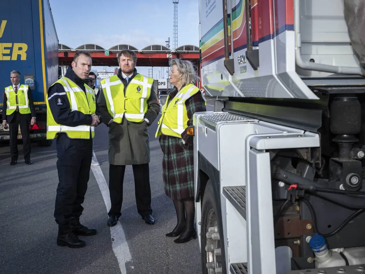 The image shows a group of people standing next to a truck on a road, with a bridge in the...