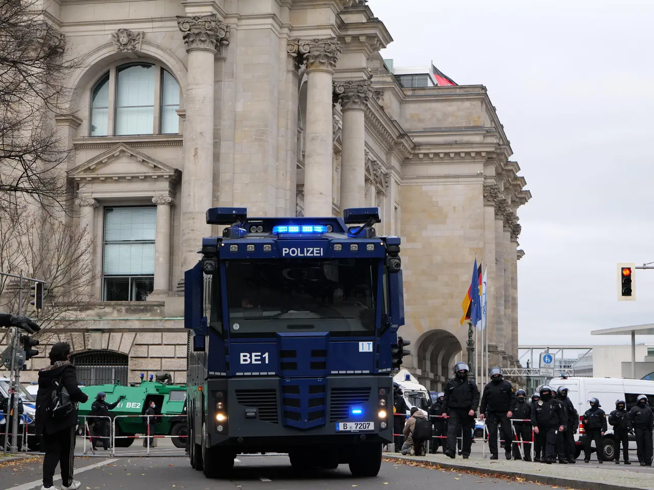 The image shows a group of police officers standing in front of a large building with windows,...