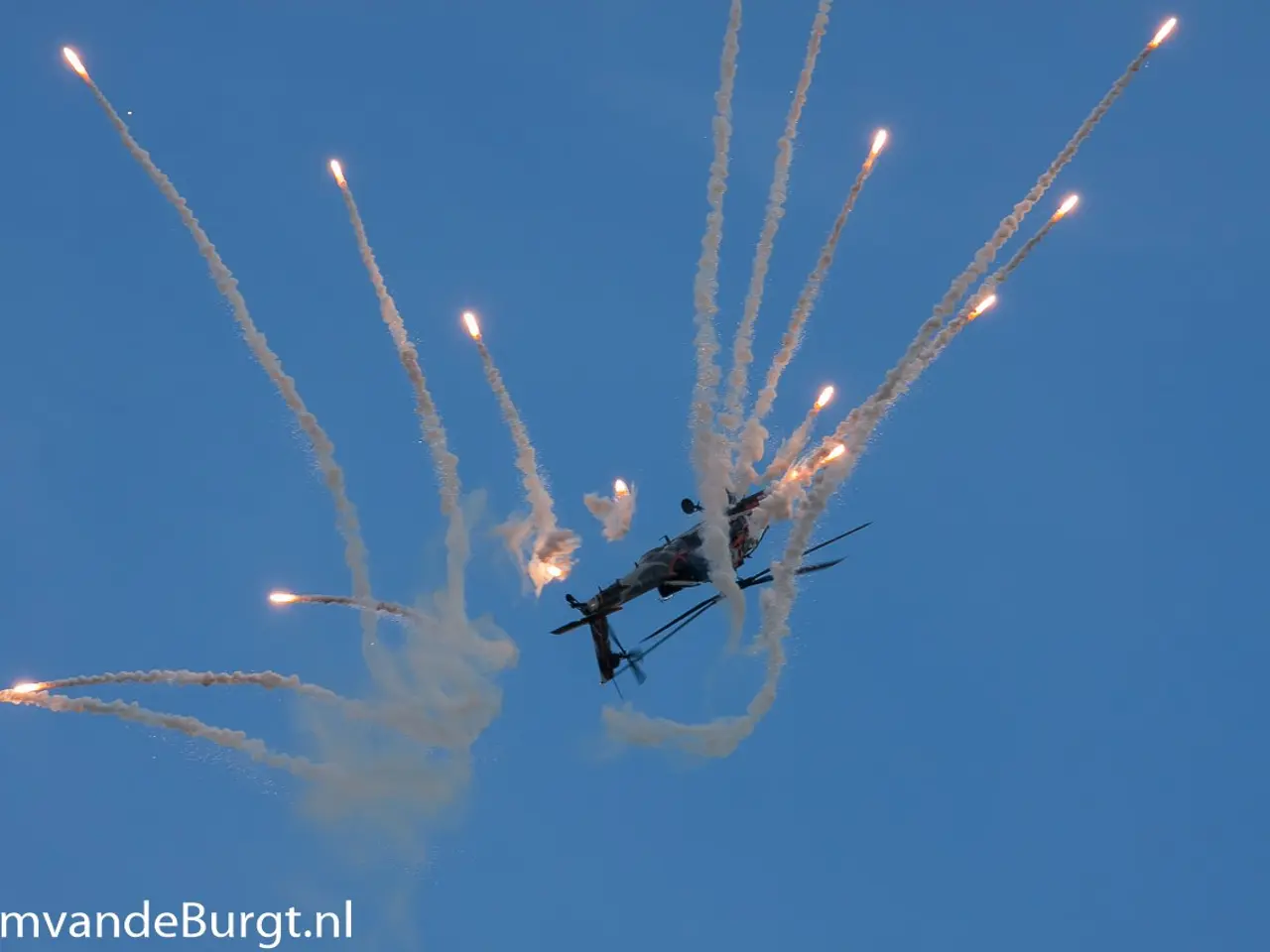 The image shows a helicopter flying through the air with smoke trailing behind it, creating a trail...