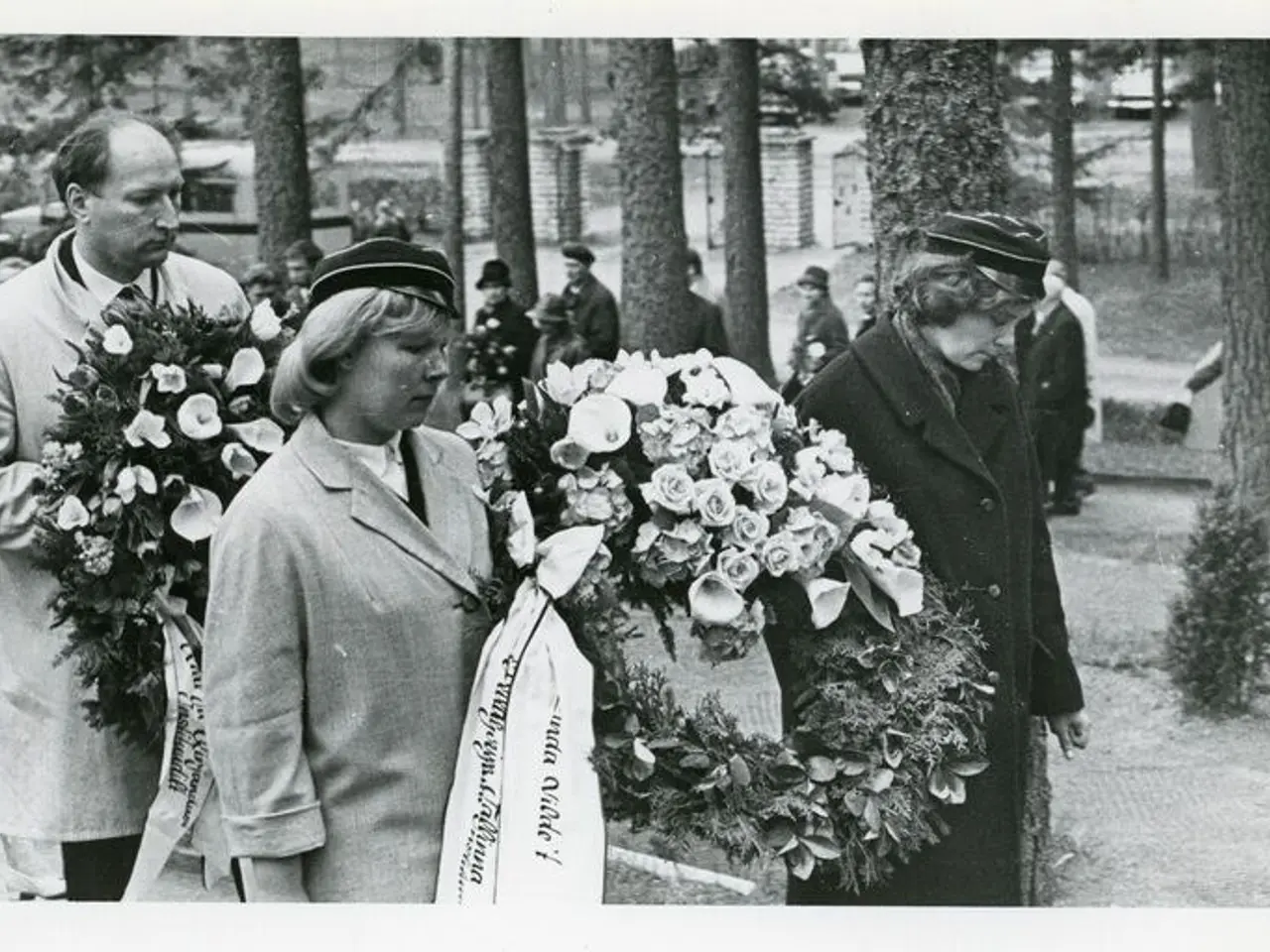 The image shows a group of people standing next to each other, each holding a bouquet of flowers....