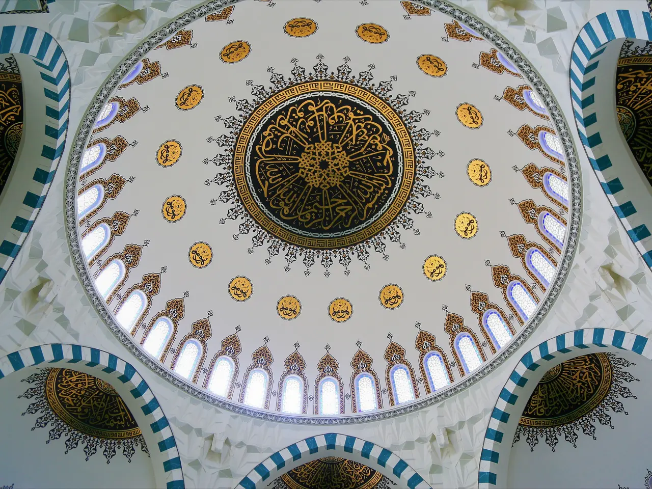 The image shows the interior of a mosque with a dome on top of it. The walls are decorated with...