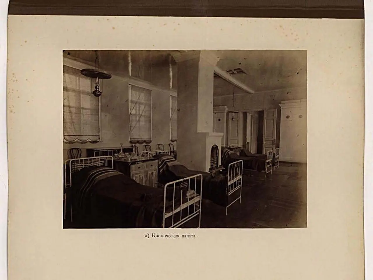 The image shows an old black and white photo of a hospital room with two pictures of beds, tables,...