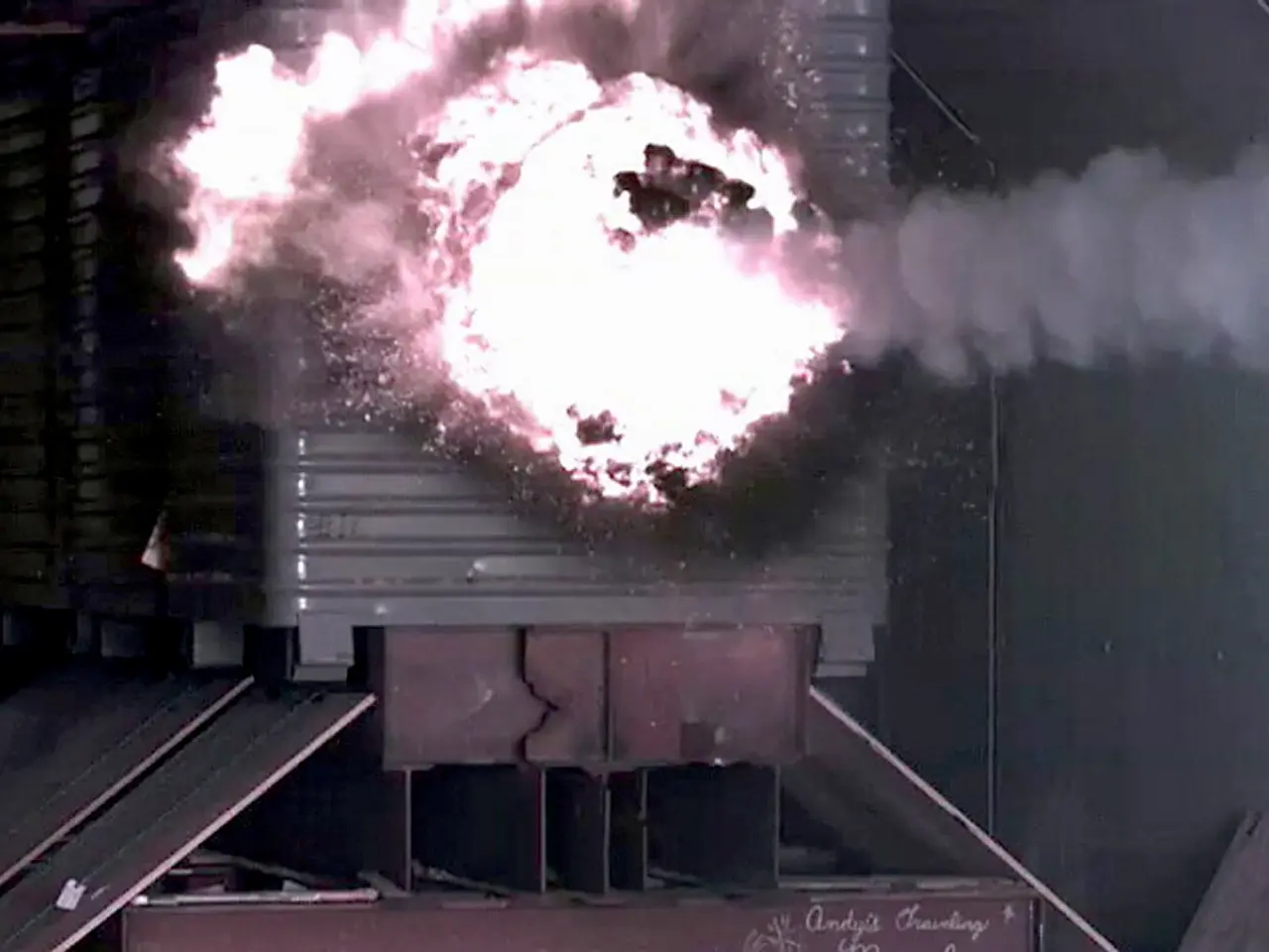The image shows a large explosion in the middle of a building, with smoke billowing out of it and a...