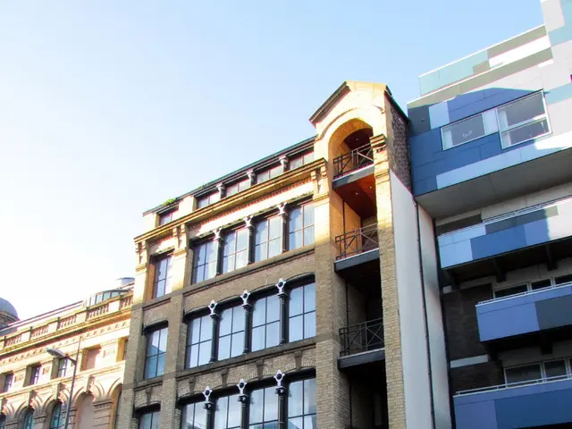 In this picture there are few buildings and there is a pole in the left corner and there is a road...