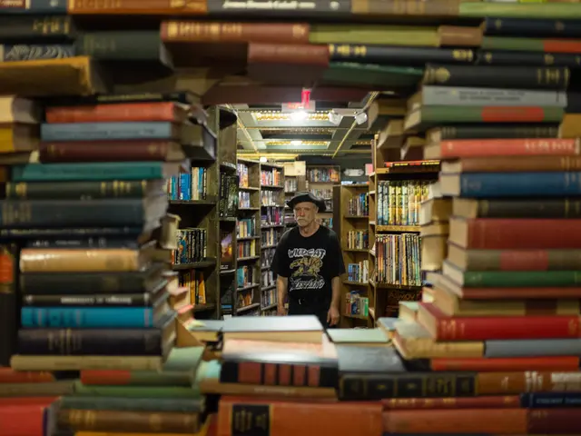 In this image, I can see the man standing. He wore a cap, T-shirt and trouser. These are the books,...