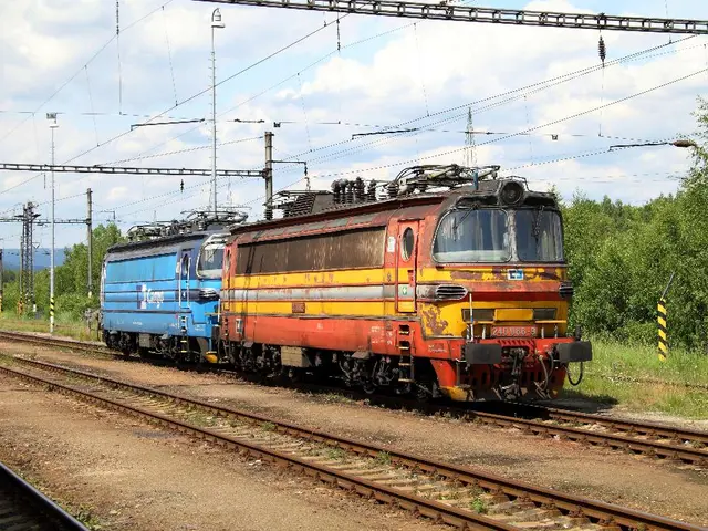In this image there is a train engine on one of the tracks, there are few electric poles and...