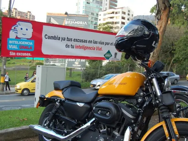 In this image there are vehicles on a road and there are a banners on that banner there is some...