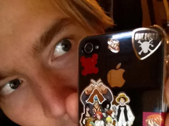 Boy in white t-shirt and black jacket is holding a mobile case in his hand and we even see some...