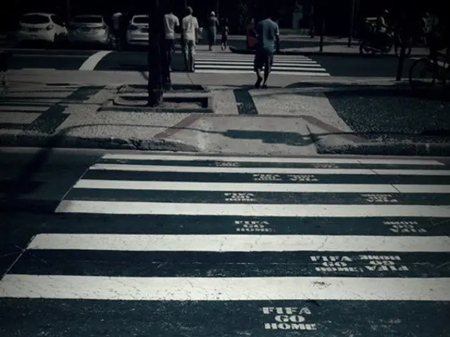 In this picture there are few people walking on zebra crossing and there are few cars in the left...