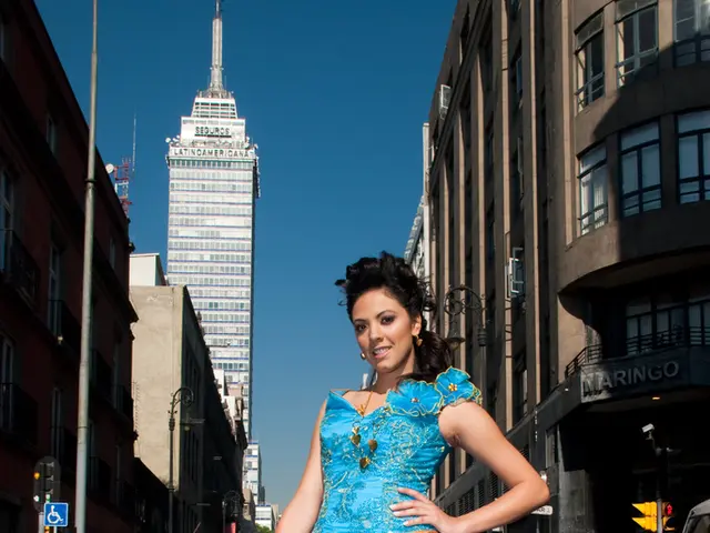 In this image we can see a woman standing on the road, grills, barrier poles, street poles, street...