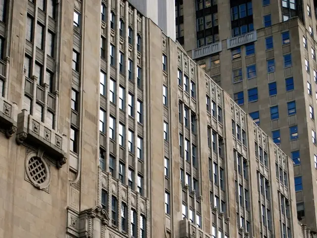 In the foreground of this image, there is a banner on a building. At the top, there are buildings.