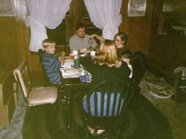 This is a picture of five people sitting on the chair around the dining table and there are two...