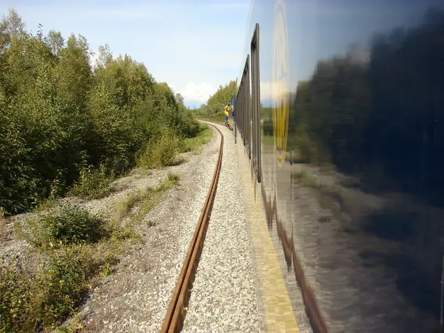 This image is clicked outside. There is a train on the right side. There are trees on the left...