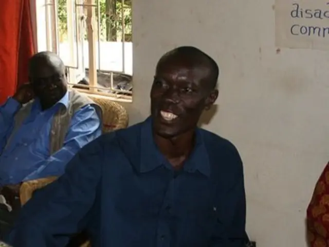 In this image there are people sitting on chairs, in the background there is a wall, for that wall...