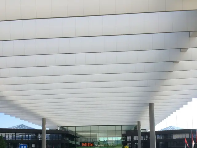 In this image few bicycles and vehicles are on the pavement. Left side there is a banner. Right...