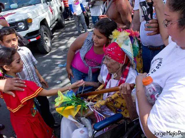 In this image we can see many people. There is a vehicle. Also there is a lady sitting on a...