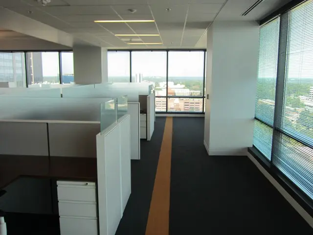 It is an interior part of an office room, in the left side there are work desks which are in white...