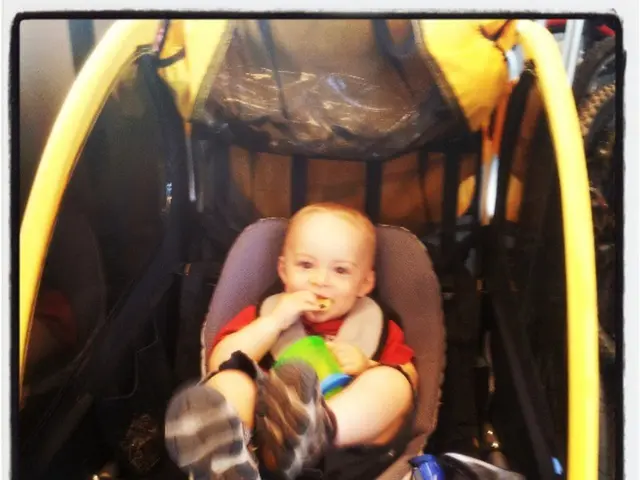 In the image we can see there is a kid sitting on the chair and there is a helmet. The kid is...