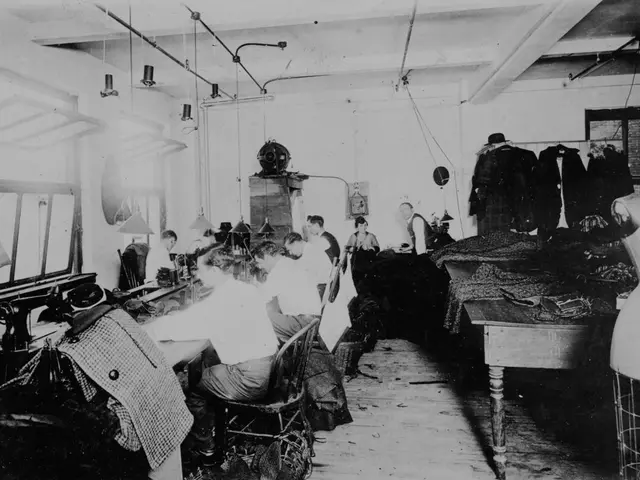 This is a black and white image in this image people are sitting on chairs and there are sewing...