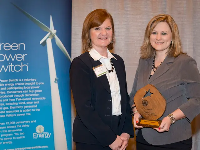 In this image we can see two women standing in a room, a woman is holding an award and there is...