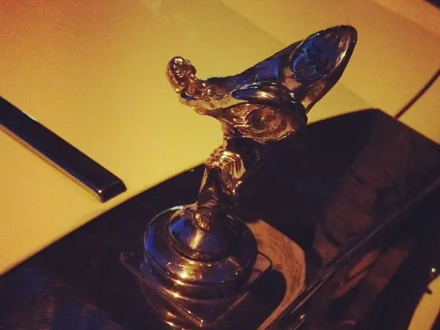 In this picture there is a vehicle and there is text on the vehicle and there is a sculpture on the...