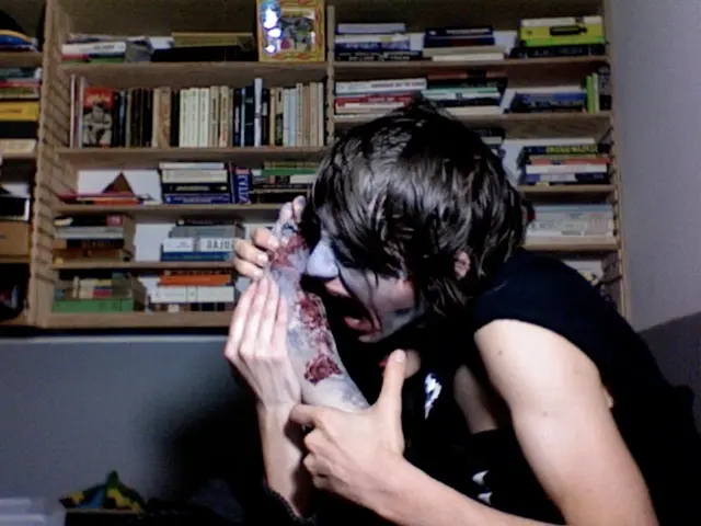 In the center of the image there is a woman. Int he background we can see many books arranged in...