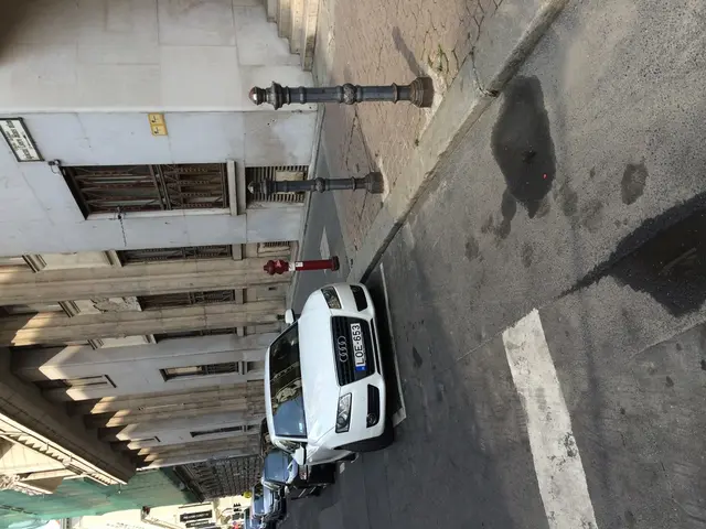 This picture is taken on the road. In this image, in the middle, we can see few cars which are...