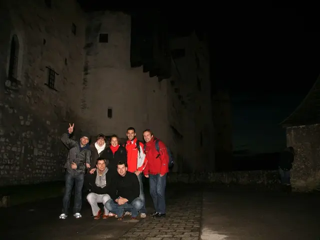 The picture is taken during night time. In the center of the picture there are people. In the...