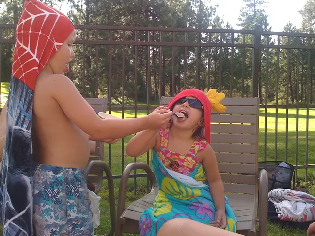 To the left side of the image there is a boy with short and a cloth on his head. He is holding the...