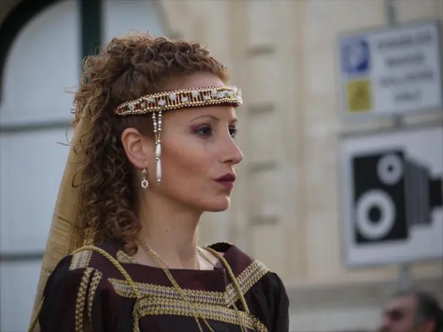 In this image there is a girl who is wearing the costume. There is a hair band to her forehead. In...