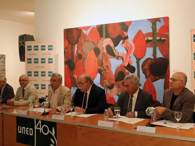 This is an inside view. Here I can see few men wearing suits, sitting on the chairs in front of the...