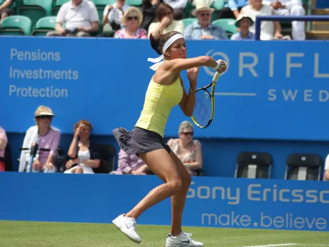 A lady with yellow color top is running. She is holding a racket in her hand. She is in the court....