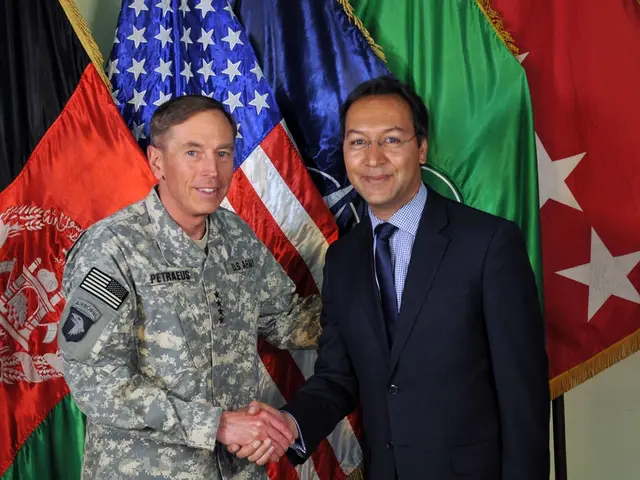 In the middle of the image two persons are standing and smiling. Behind them there are some flags....