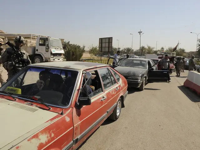 In this image we can see some vehicles moving on the road and there are some persons standing and...