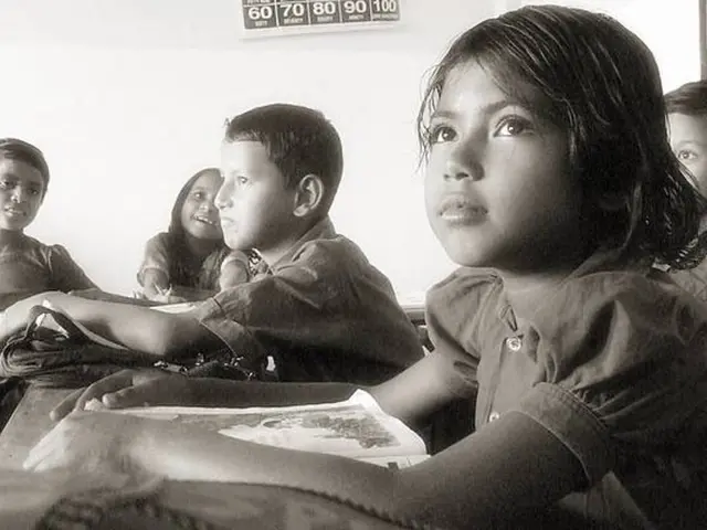 In this picture there are group of people sitting and there are books and bags on the tables. At...