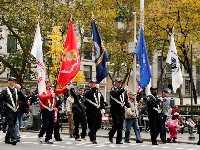 In the center of the image we can see people holding flags. On the right there is a pole. In the...