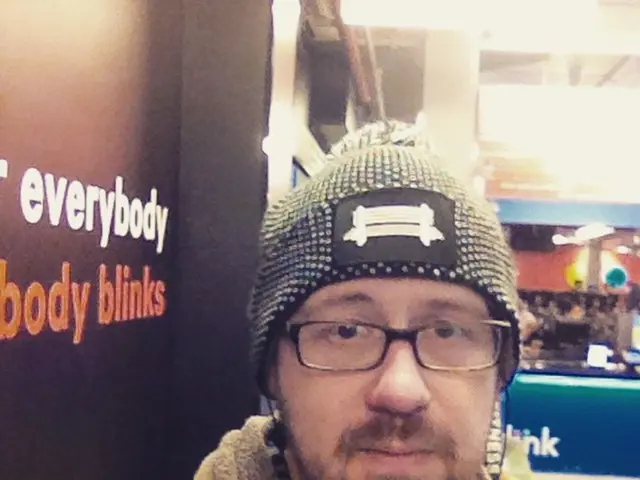 In this picture we can observe a man wearing a sweater, spectacles and a cap on his head. On the...