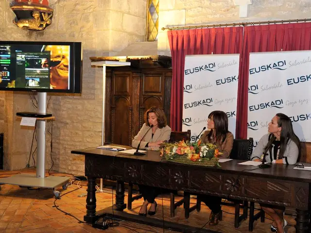 There is a table at here. Three women are sitting on the chairs and two women looking into the T....