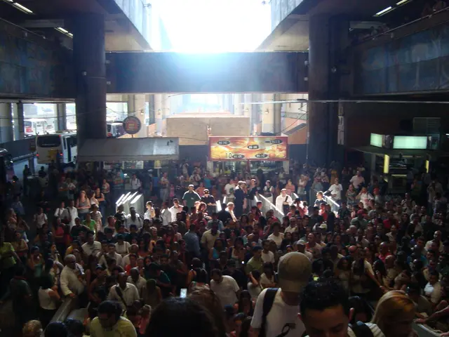 In this image there are many people standing. Behind them there are stalls. In the background there...