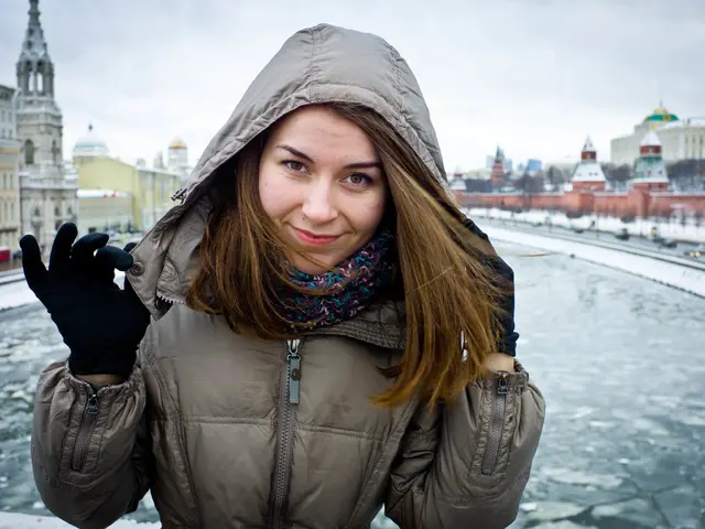 There is a a woman, she is wearing a jacket and behind the woman there is a water surface and the...