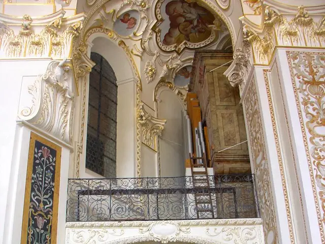 In this picture we can see wall, photos, carvings, railing, wall, mesh and few objects.