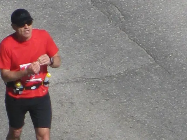 In this image we can see a man walking. In the background there is a road.